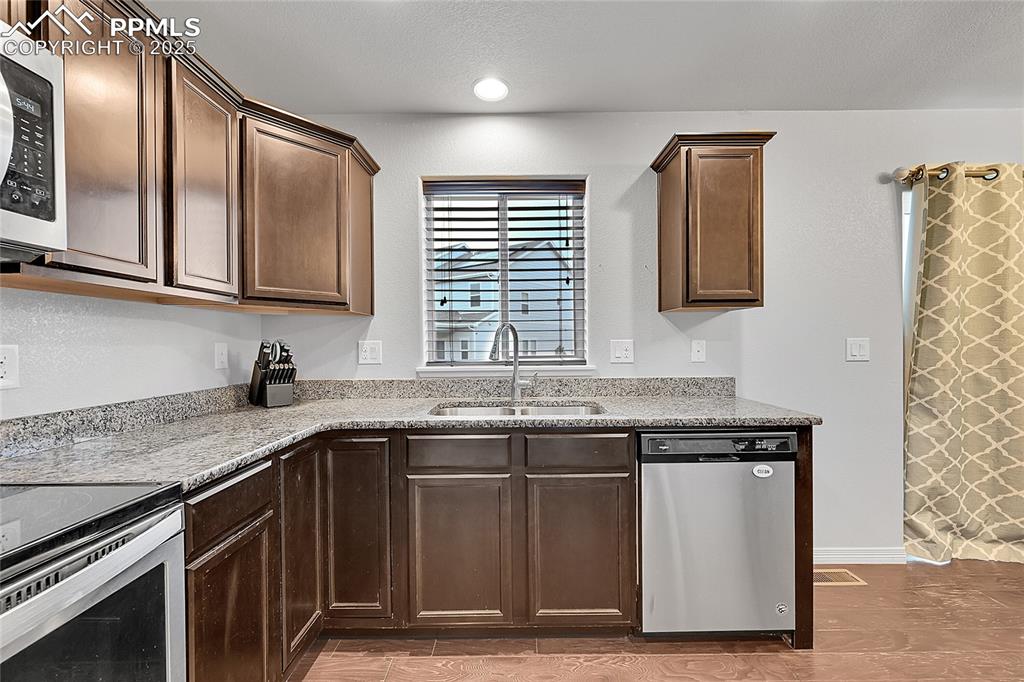 Image 14 of 29: Kitchen featuring dark brown cabinetry, light wood-type flooring, light sto