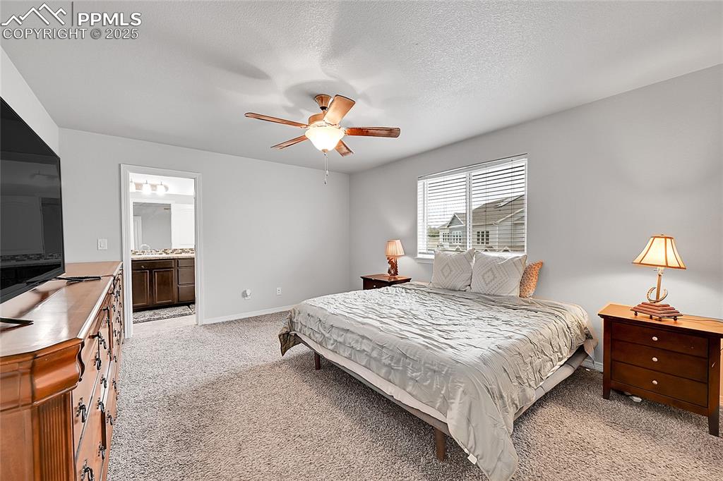 Image 20 of 29: Bedroom with baseboards, ceiling fan, ensuite bath, and light carpet