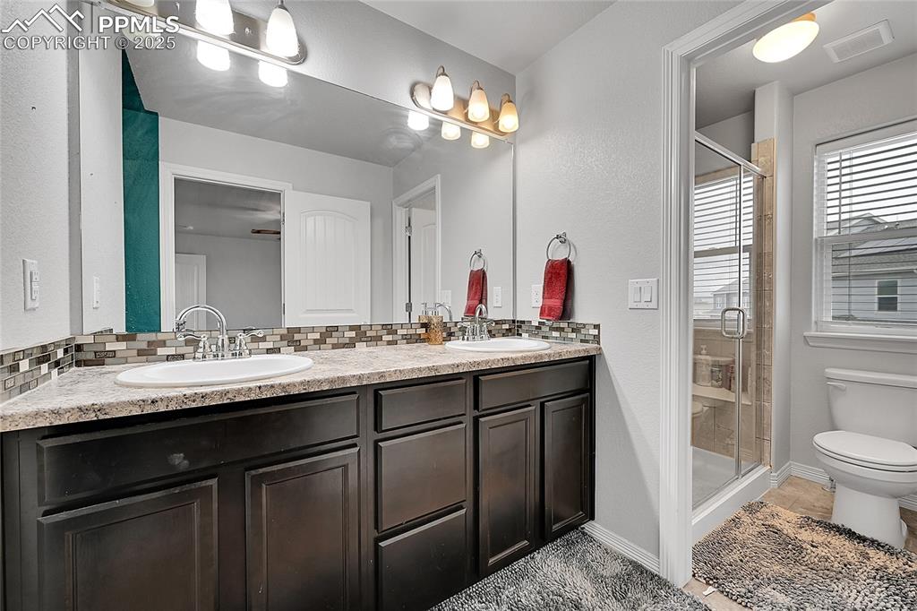 Image 22 of 29: Full bathroom featuring toilet, visible vents, a sink, and tasteful backspl