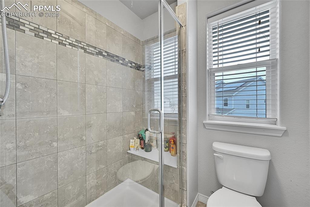 Image 23 of 29: Bathroom featuring a healthy amount of sunlight, toilet, and a shower stall
