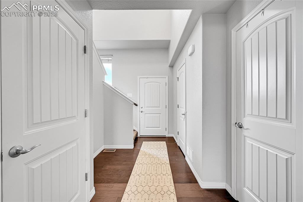 Image 5 of 29: Corridor featuring dark wood-type flooring, baseboards, and stairs