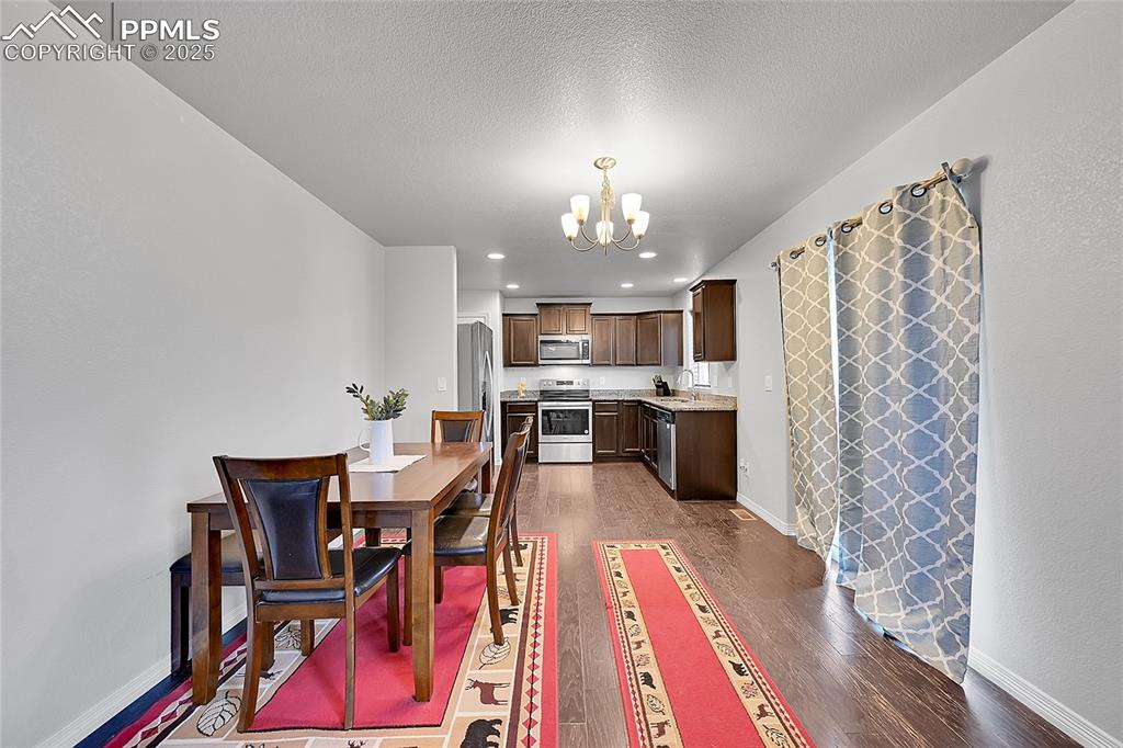 Image 8 of 29: Dining area featuring baseboards, dark wood finished floors, and a chandeli