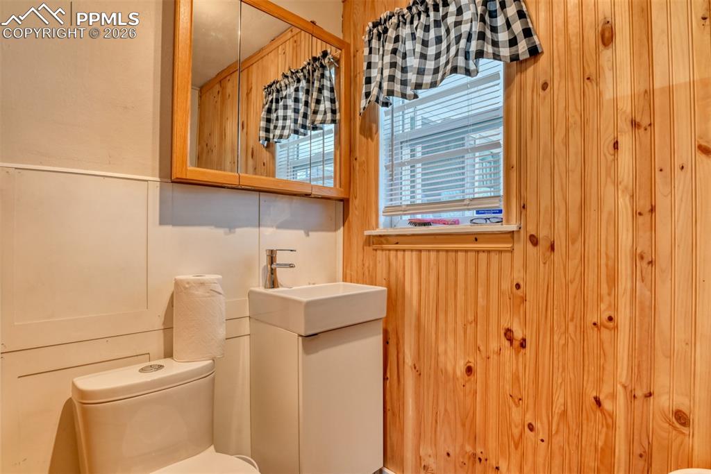 Image 10 of 47: Bathroom with wooden walls, vanity, and toilet