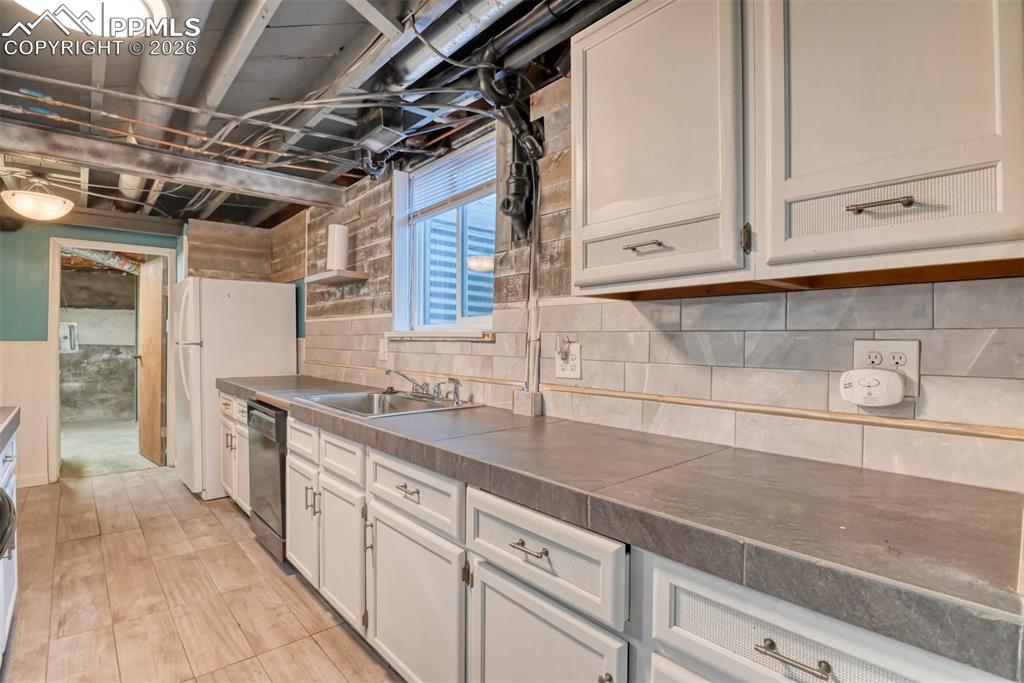 Image 22 of 47: Second Kitchen with freestanding refrigerator, white cabinets, dishwasher,