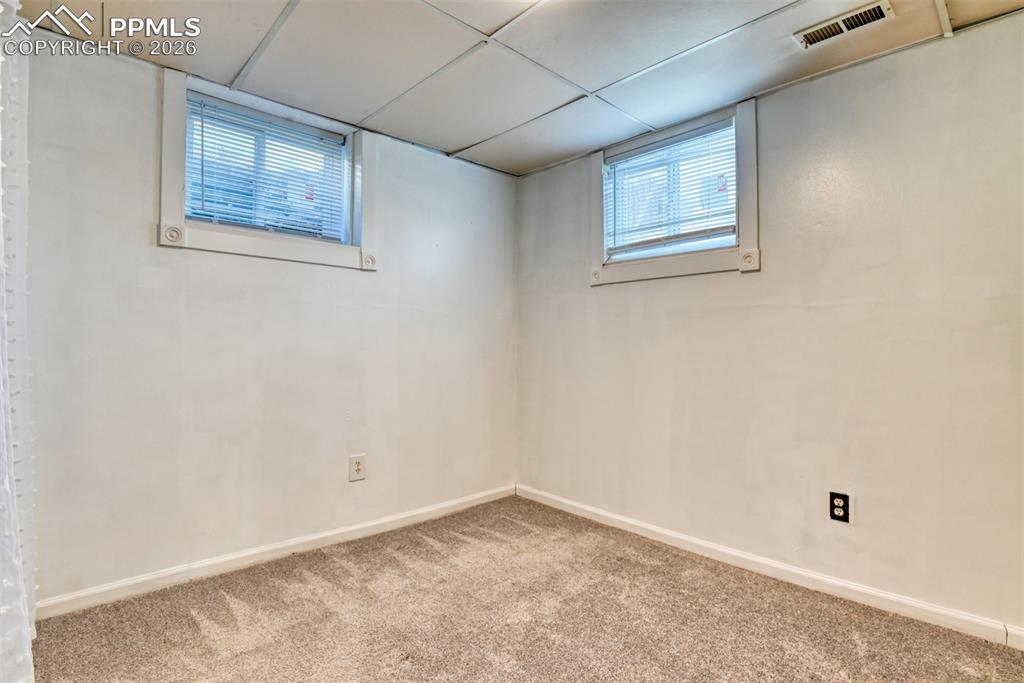 Image 25 of 47: Basement featuring carpet flooring, visible vents, a drop ceiling, and base