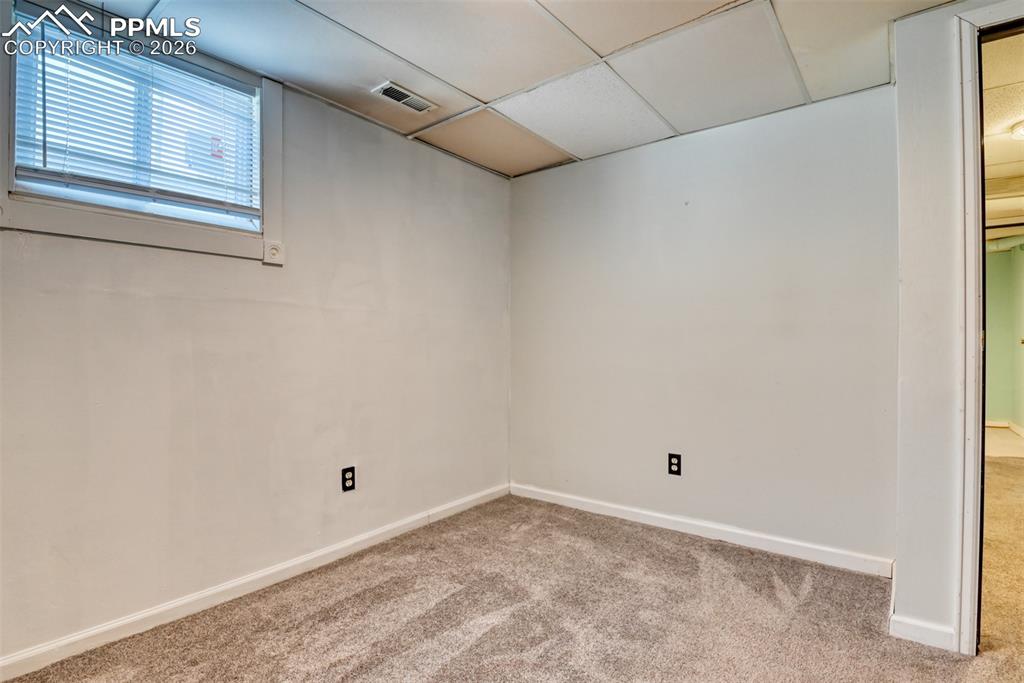 Image 31 of 47: Carpeted spare room with visible vents, baseboards, and a drop ceiling