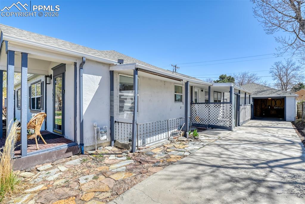 Image 44 of 47: View of side of property with concrete driveway, roof with shingles, covere