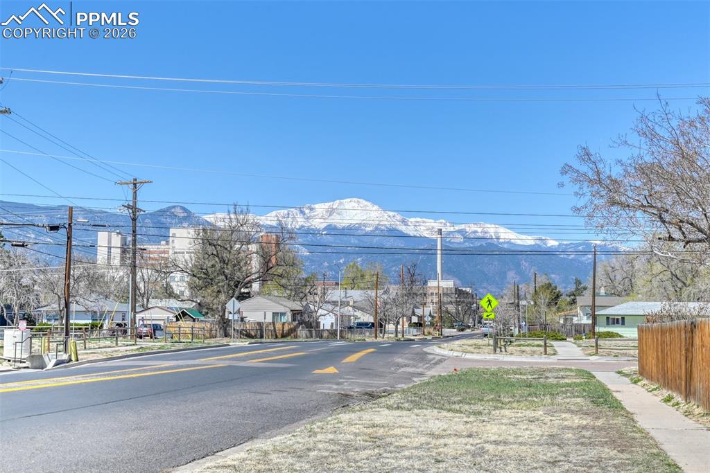 Image 47 of 47: View of street featuring traffic signs, sidewalks, a mountain view, and a r