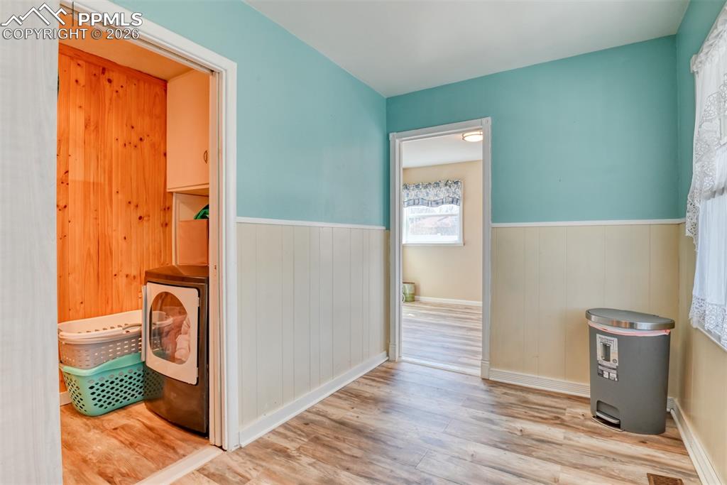 Image 9 of 47: Hall featuring washer / dryer, a wainscoted wall, and wood finished floors
