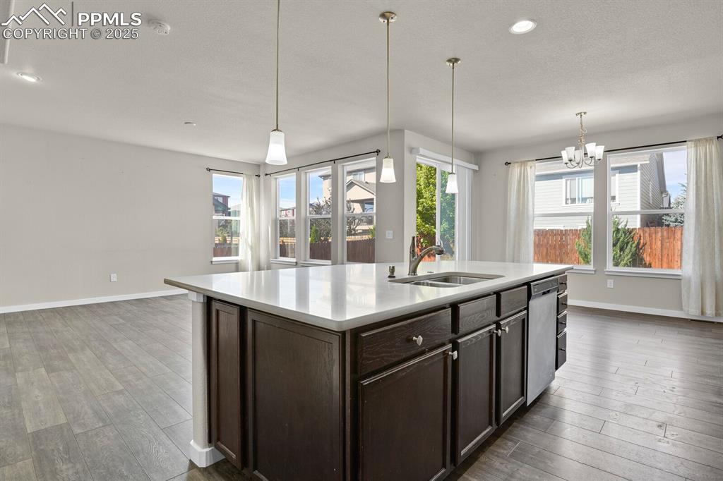Image 12 of 31: Kitchen featuring dark brown cabinetry, hanging light fixtures, a center is
