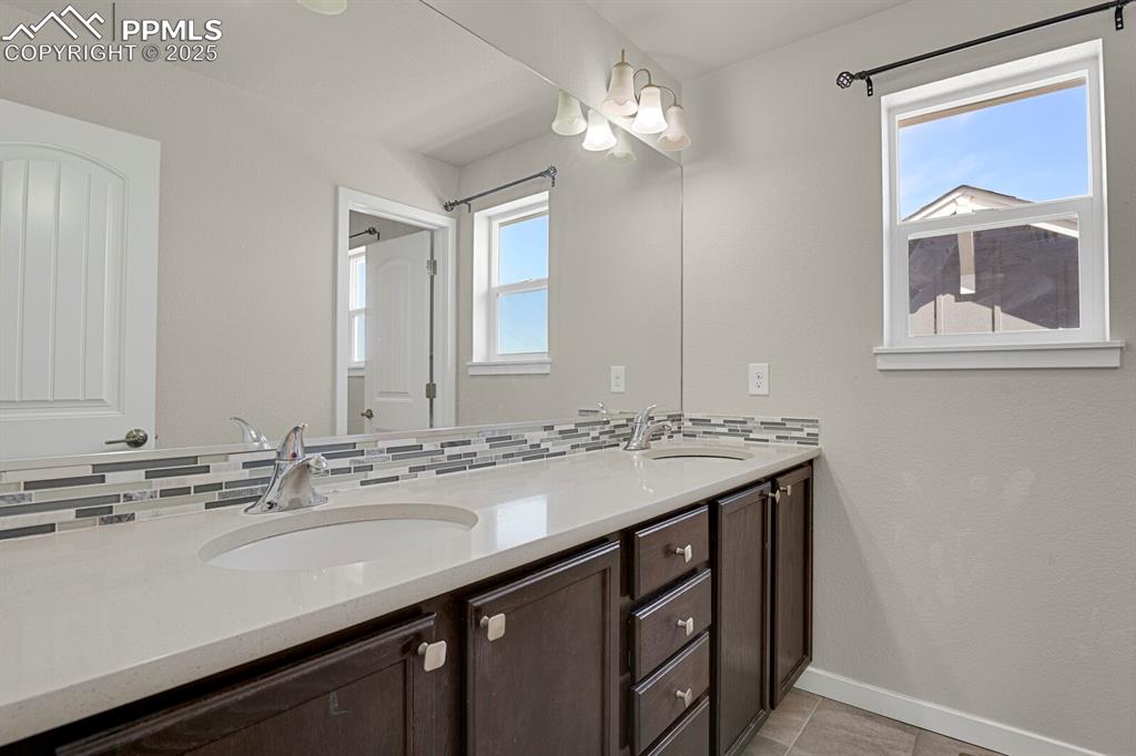 Image 19 of 31: Bathroom with double vanity, healthy amount of natural light, tasteful back