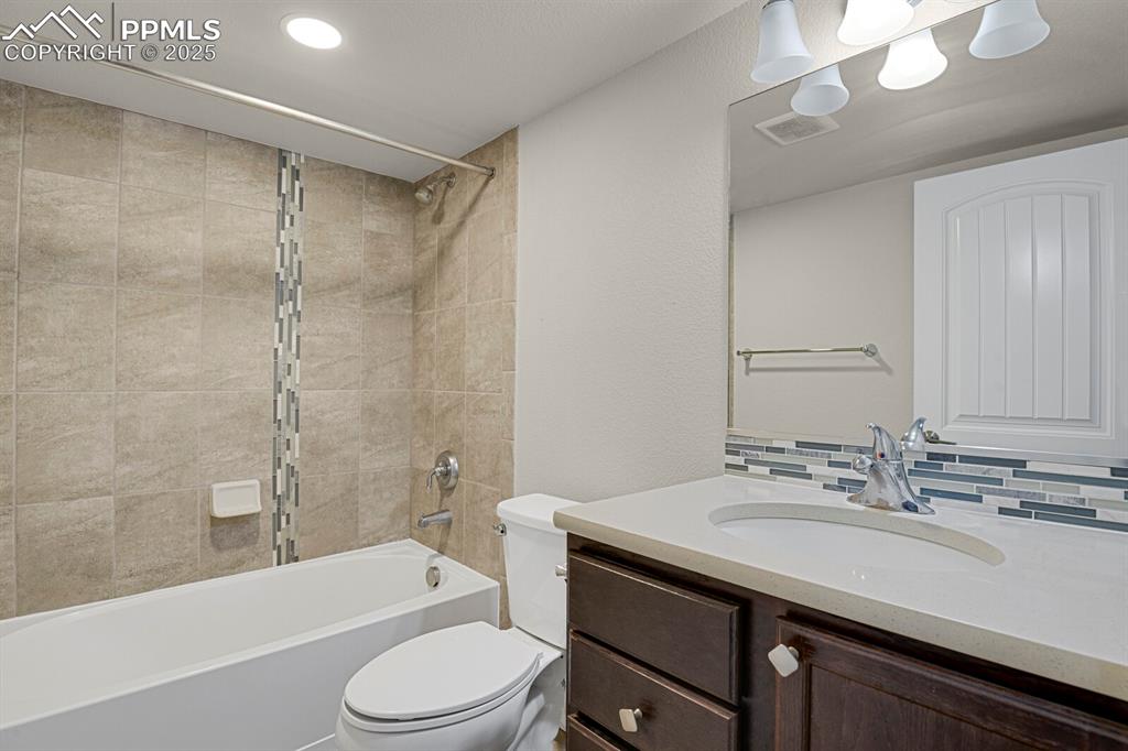 Image 27 of 31: Bathroom featuring vanity, tub / shower combination, decorative backsplash,