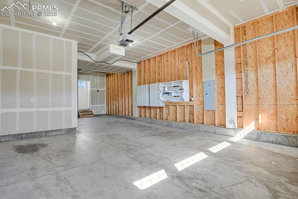 Image 29 of 31: Garage with electric panel and a garage door opener
