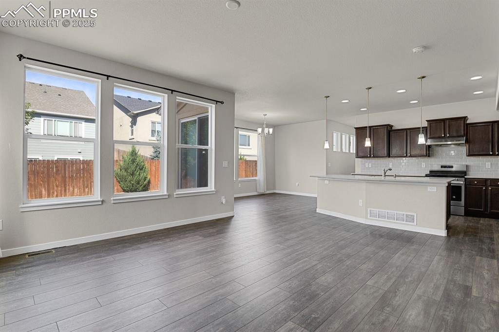 Image 6 of 31: Kitchen featuring dark brown cabinetry, a kitchen island with sink, a chand
