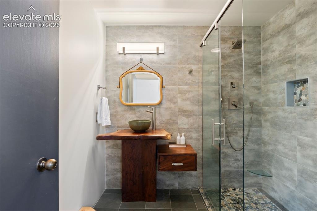 Image 24 of 36: Updated main level bathroom with glass-enclosed shower.