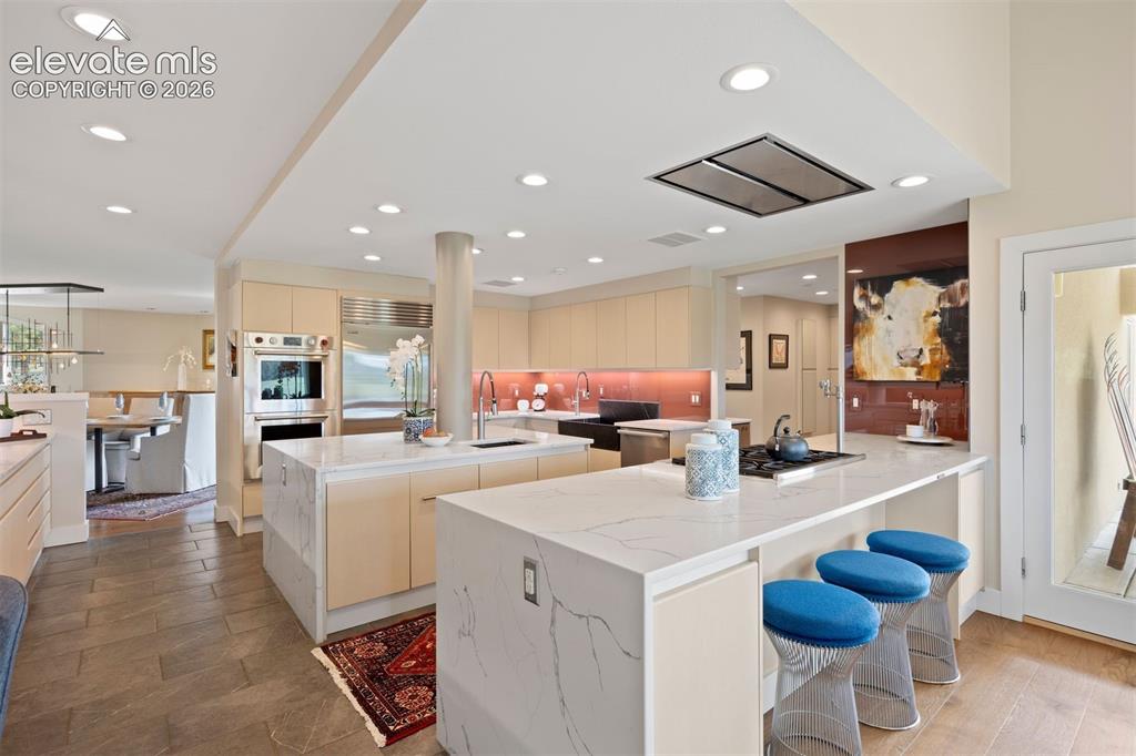 Image 7 of 36: Spacious kitchen featuring a massive marble waterfall island and peninsula 