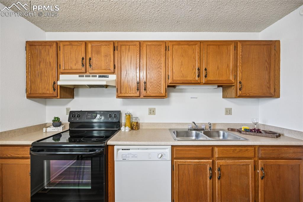 Image 12 of 28: Kitchen featuring black range with electric cooktop, brown cabinetry, dishw