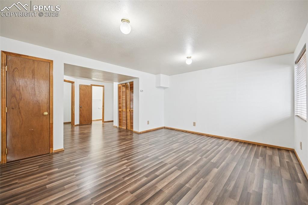 Image 16 of 28: Unfurnished room featuring dark wood-style flooring and baseboards