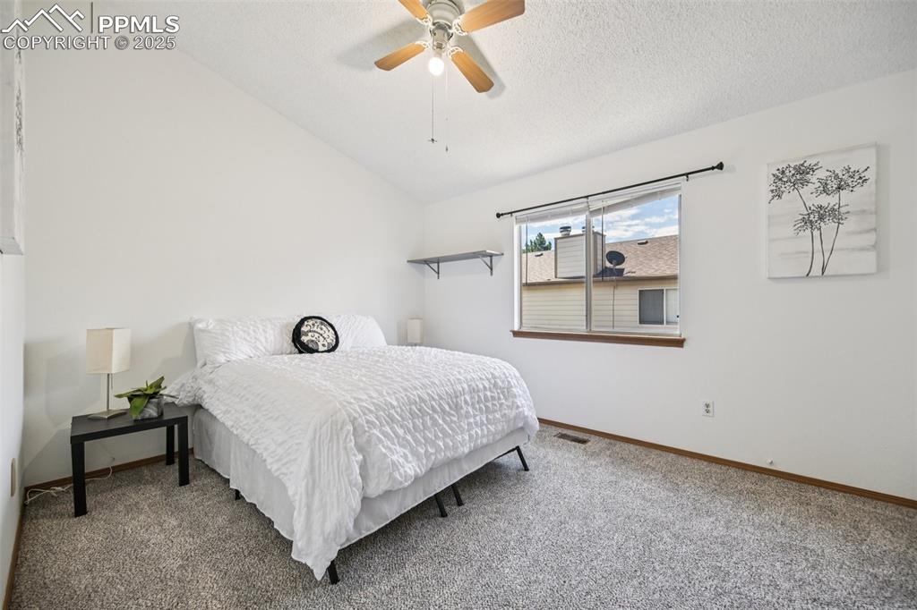 Image 17 of 28: Bedroom featuring lofted ceiling, carpet, a ceiling fan, and a textured cei