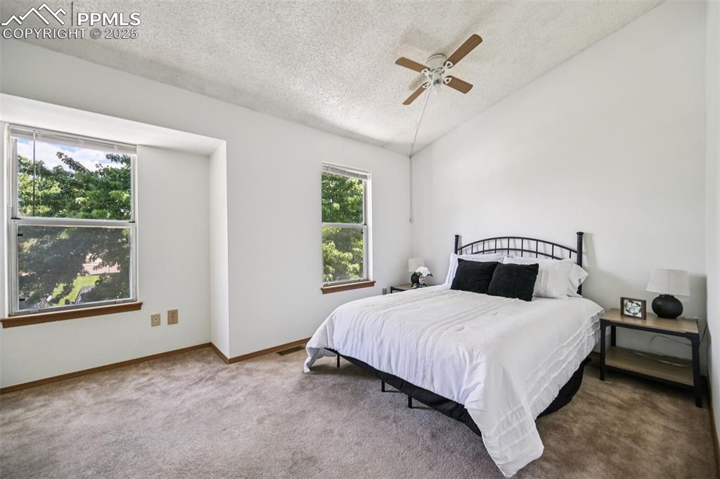 Image 22 of 28: Bedroom featuring vaulted ceiling, a textured ceiling, carpet floors, and c