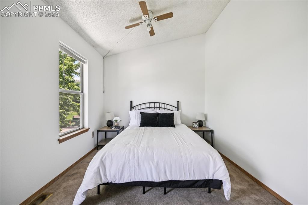 Image 23 of 28: Carpeted bedroom with a textured ceiling and a ceiling fan