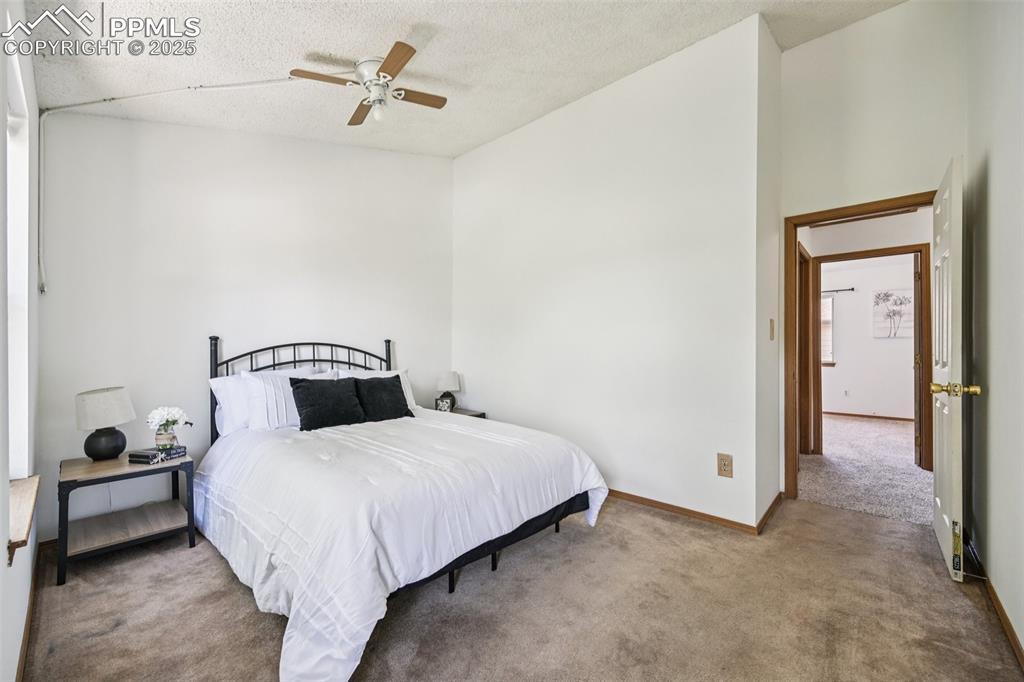 Image 24 of 28: Bedroom with carpet floors, ceiling fan, and a textured ceiling