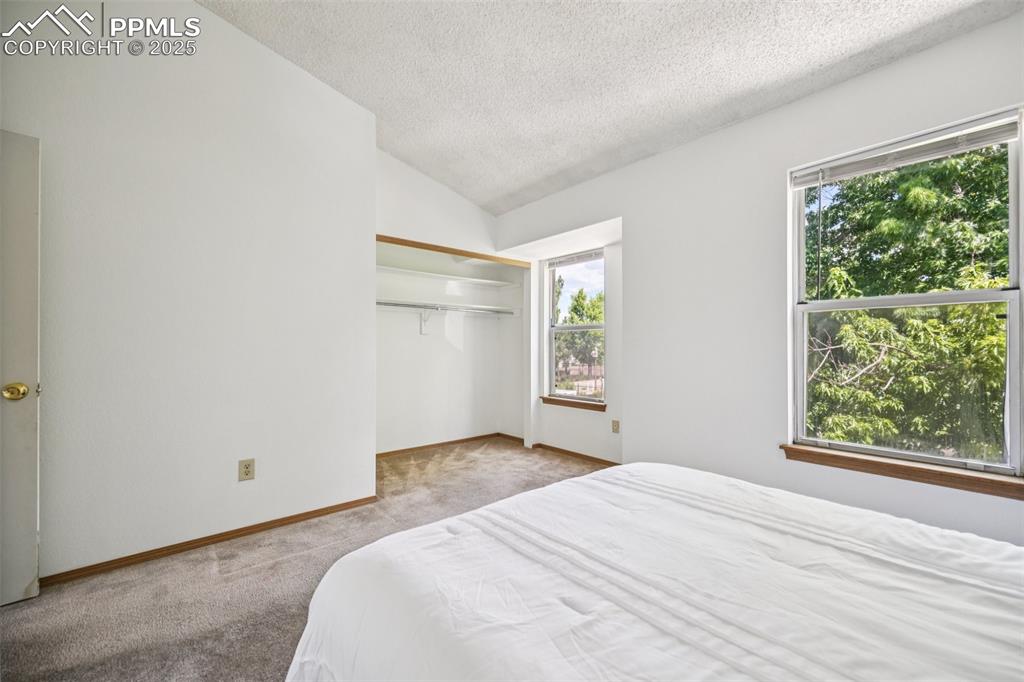 Image 25 of 28: Bedroom featuring vaulted ceiling, carpet flooring, a textured ceiling, and
