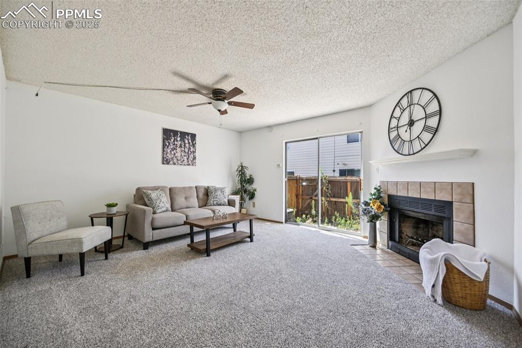 Image 3 of 28: Living area with carpet flooring, a textured ceiling, a fireplace, and ceil