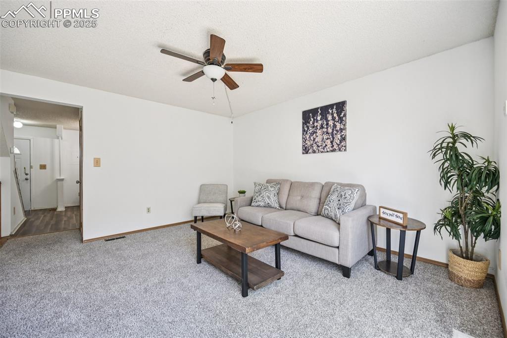 Image 4 of 28: Living area with carpet floors, a textured ceiling, and ceiling fan