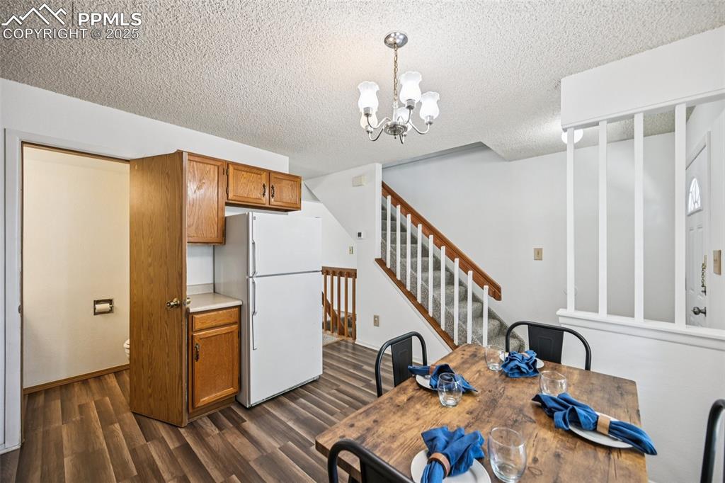 Image 8 of 28: Unfurnished dining area with dark wood finished floors, a chandelier, a tex