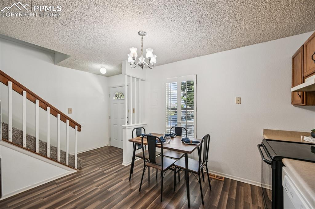 Image 9 of 28: Dining area with a textured ceiling, a chandelier, dark wood-type flooring,