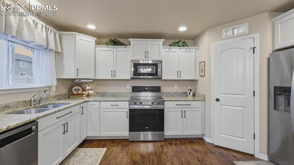 Image 18 of 50: The Eat-In Kitchen boasts white cabinetry, granite countertops, a large pan