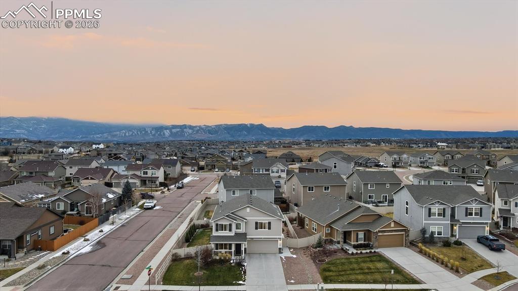 Image 3 of 50: Aerial view of the front of the home and mountain views behind.