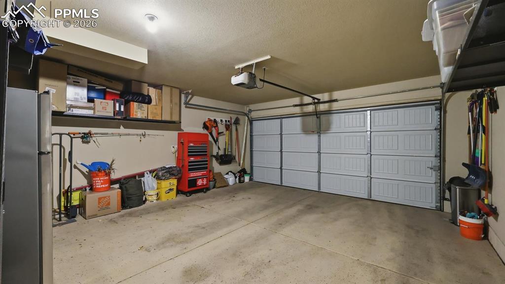 Image 40 of 50: Two car attached garage with door opener and attached black storage racks t