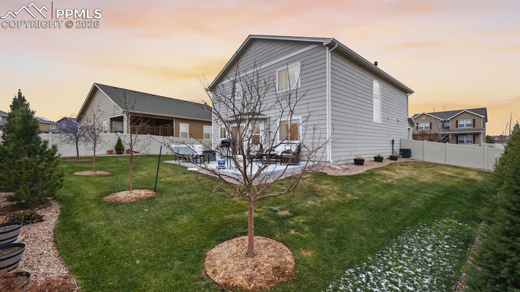 Image 43 of 50: Nicely landscaped yard with a variety of trees, lush grass, and concrete pa