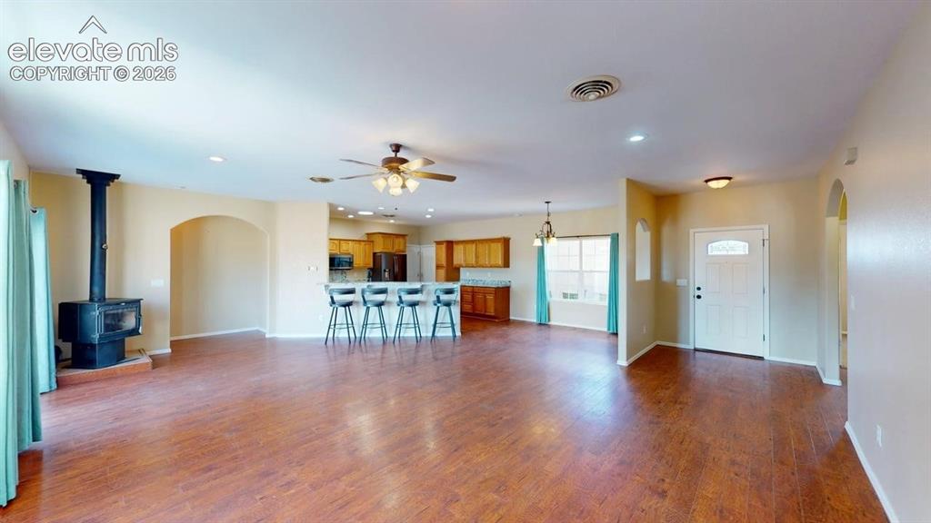 Image 14 of 50: Expansive living area featuring wood-finish flooring, a freestanding wood-b