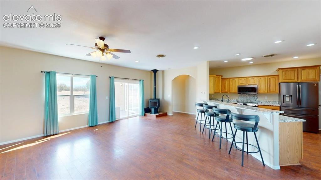 Image 16 of 50: Open-concept living area featuring wood-finish flooring, a ceiling fan, and