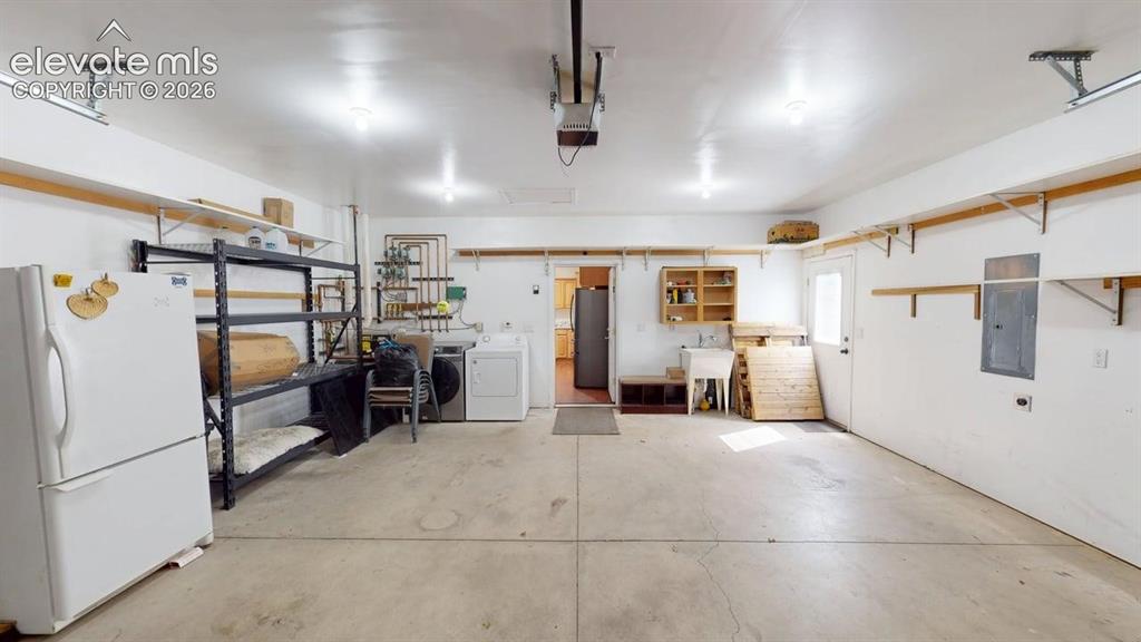 Image 18 of 50: Concrete flooring with overhead lighting, utility sink, and built-in shelvi