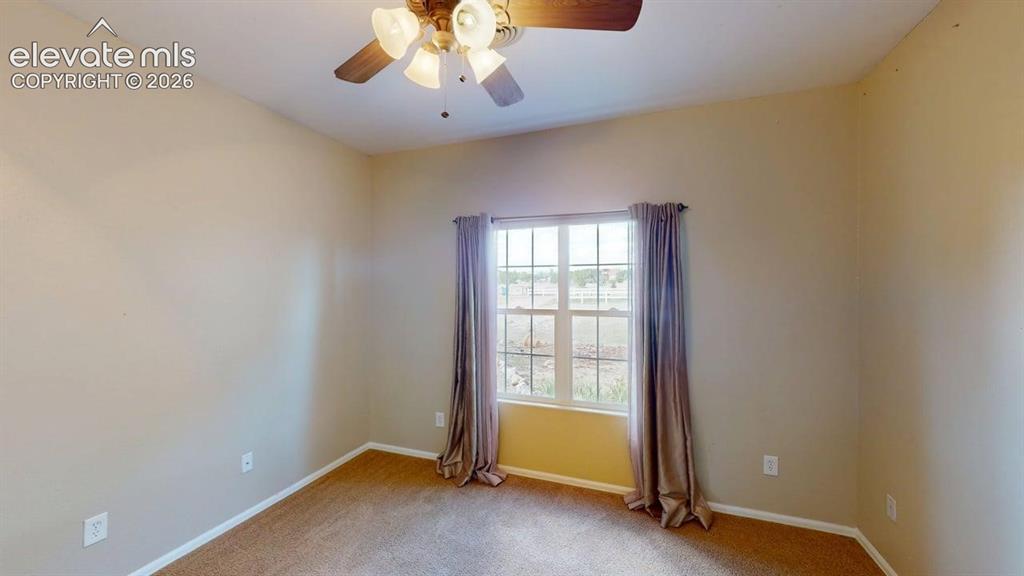 Image 24 of 50: Wall-to-wall carpeting, window with grid panes, and a ceiling fan with inte