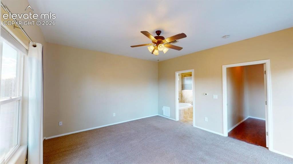 Image 31 of 50: Carpeted room featuring a ceiling fan, window, and two doorways