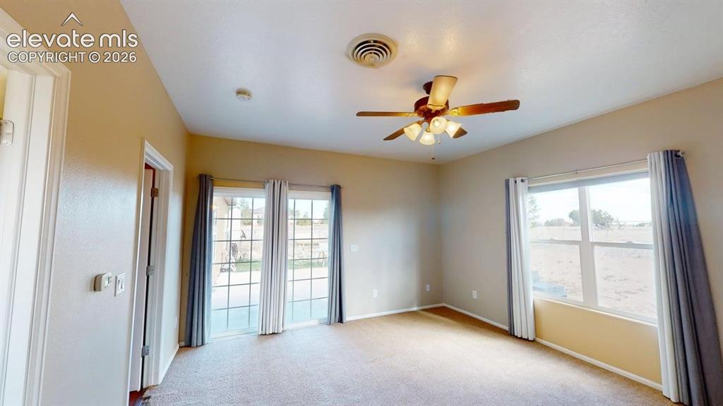 Image 32 of 50: Neutral tone wall paint, carpet flooring, a ceiling fan with integrated lig