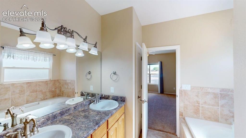 Image 35 of 50: Dual vanity with integrated sinks, full-width mirrors, warm wood-finish cab