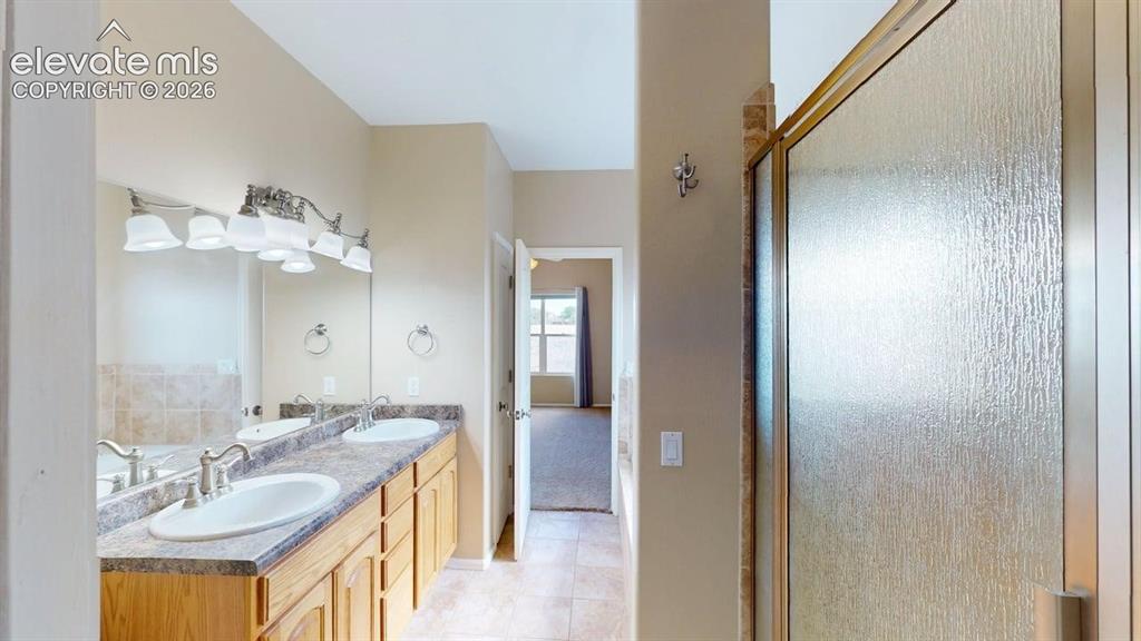 Image 36 of 50: Dual vanity with undermount sinks, wood-finish cabinetry, and patterned cou