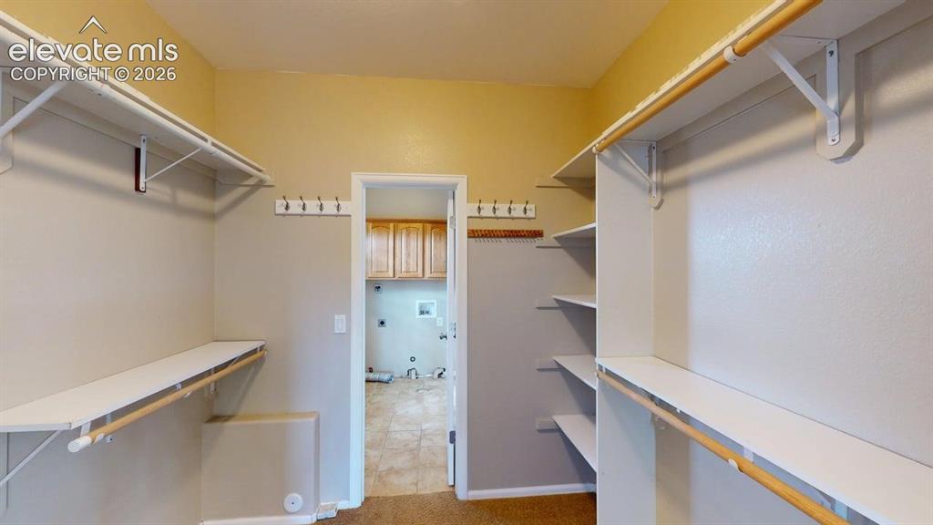 Image 37 of 50: Walk-in closet with integrated shelving and hanging rods
