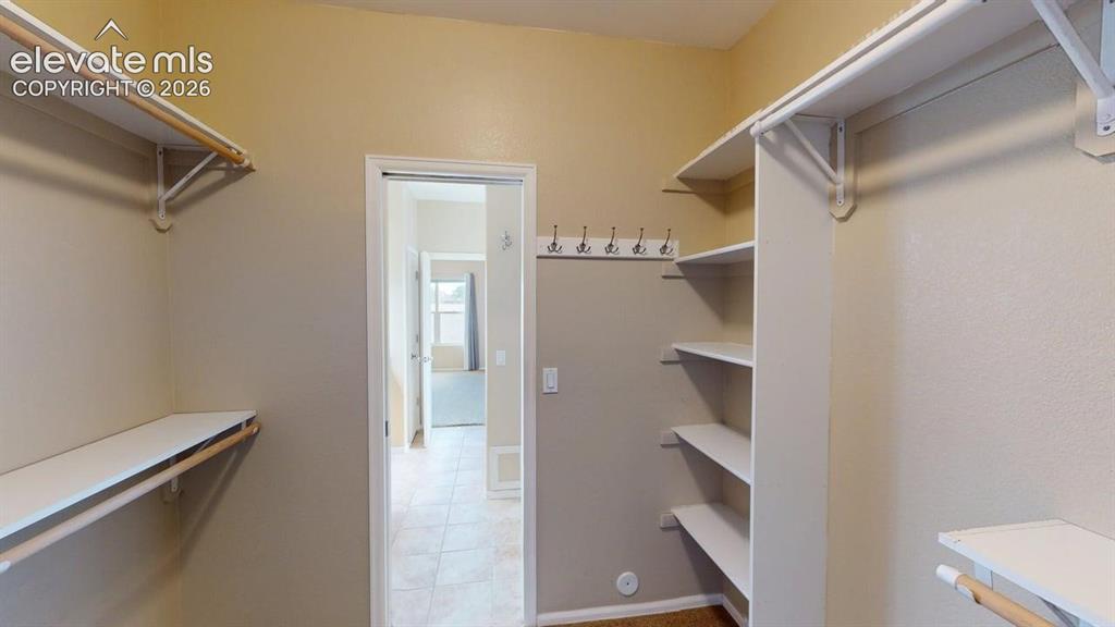 Image 38 of 50: Walk-in closet featuring white shelving, multiple hanging rods, and wall-mo