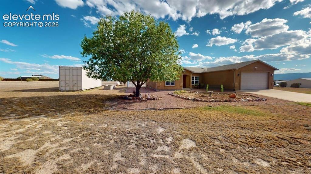 Image 4 of 50: Single-story residence with an attached garage, landscaped rock garden, and