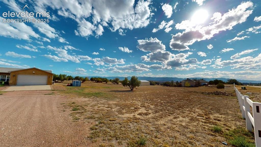 Image 46 of 50: Expansive property with a gravel driveway, attached garage, and a white pic