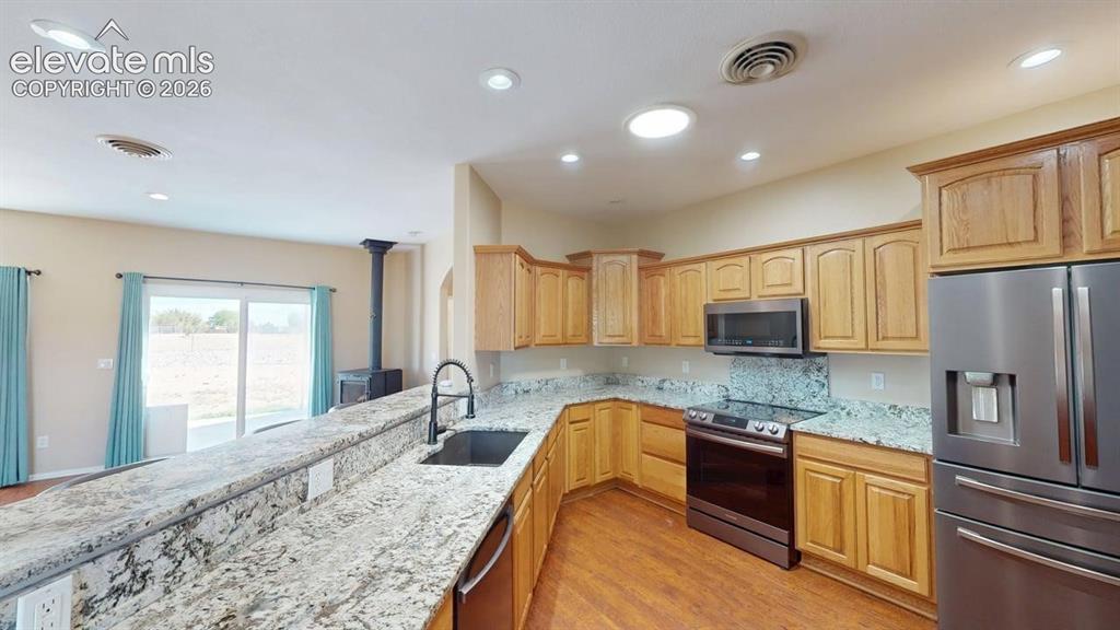 Image 7 of 50: Kitchen featuring wood-finish flooring, light wood cabinetry, stainless ste