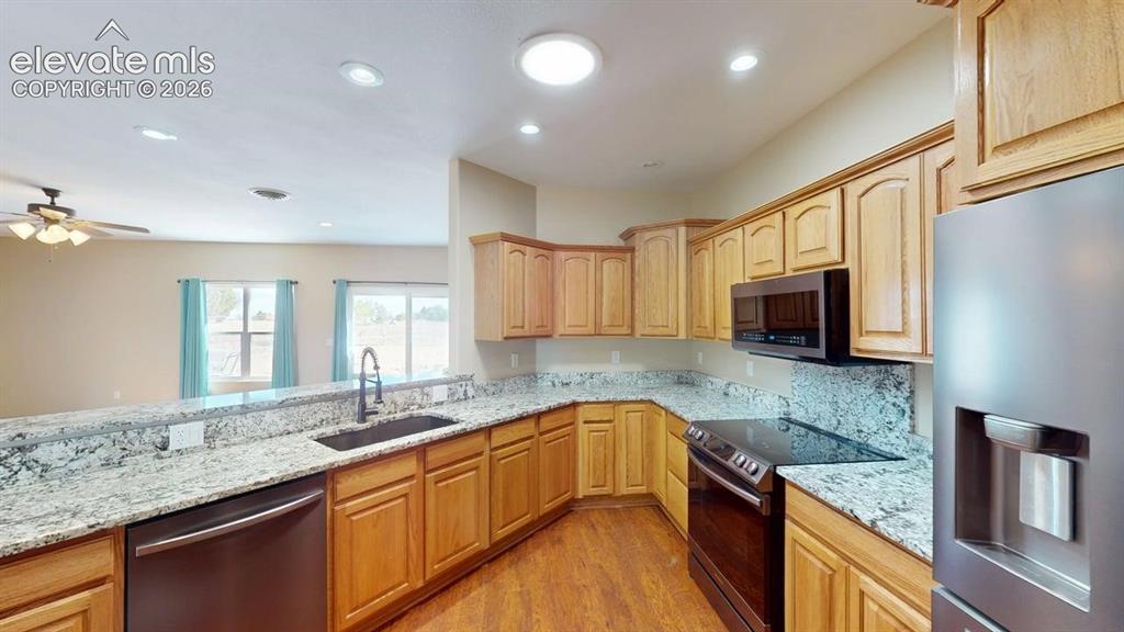 Image 8 of 50: Kitchen featuring granite countertops, wood-finish flooring, wood cabinetry