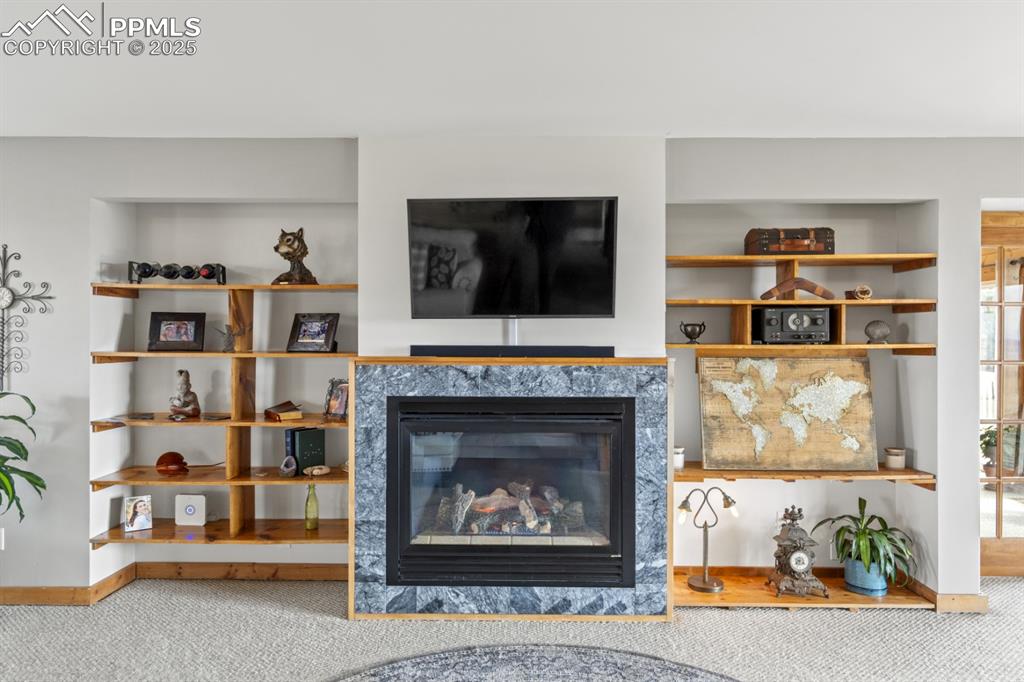 Image 9 of 25: Living area featuring carpet floors, a glass covered fireplace, and built i